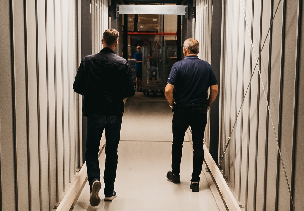 Założyciel, Trond Gule, oraz Kierownik Sprzedaży Element Logic, Øyvind Kollerud, przechodzą przez wykonany na zamówienie tunel, biegnący przez konstrukcję AutoStore w GS Bildeler w magazynie w Oslo.